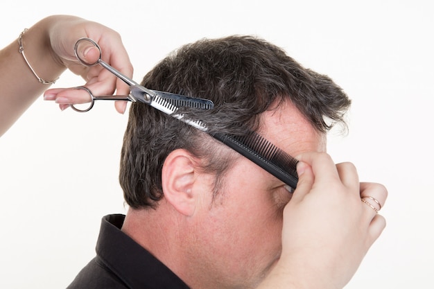 beau jeune homme ayant une coupe de cheveux fait avec des ciseaux