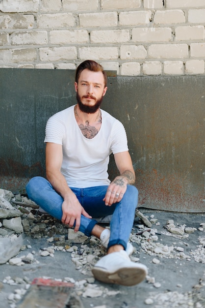 Un beau jeune homme avec une barbe dans un intérieur de style grunge