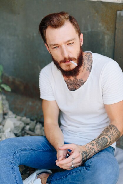 Un beau jeune homme avec une barbe dans un intérieur de style grunge