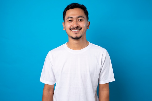 beau jeune homme avec une barbe fine souriant avec confiance sur fond bleu