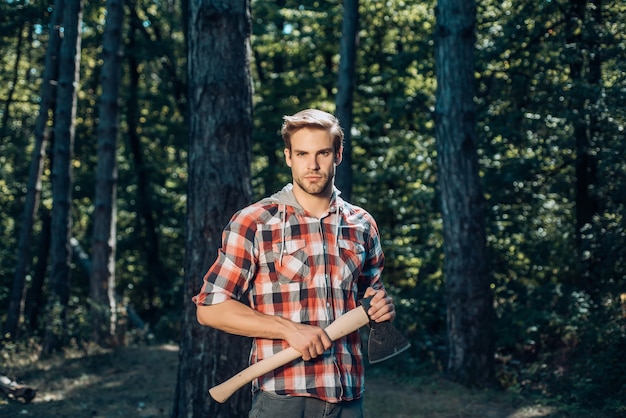 Un beau jeune homme avec une barbe porte un arbre élégant jeune homme posant comme un bûcheron bûcheron...