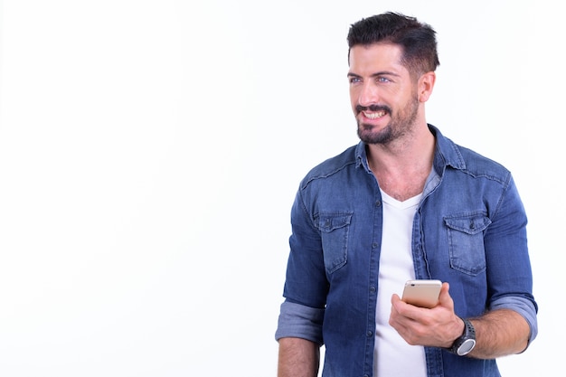 Beau jeune homme barbu hipster isolé contre un mur blanc