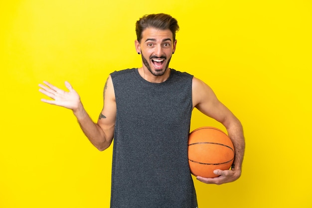Beau jeune homme de basket-ball isolé sur fond jaune avec une expression faciale choquée