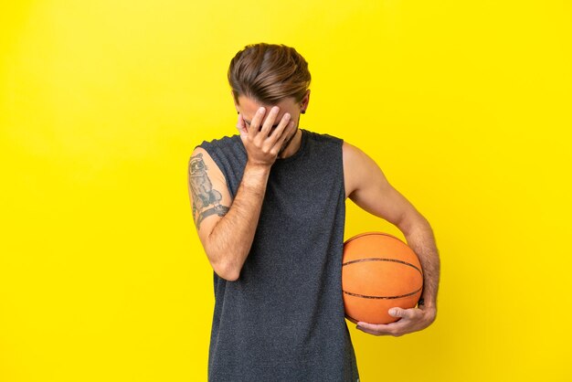 Beau jeune homme de basket-ball isolé sur fond jaune avec une expression fatiguée et malade