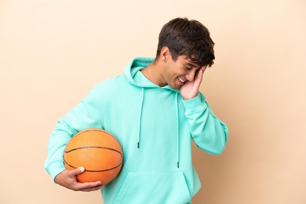 Beau jeune homme de basketteur isolé sur fond ocre en riant