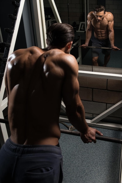 Beau jeune homme beau et séduisant avec un corps musclé relaxant dans la salle de sport