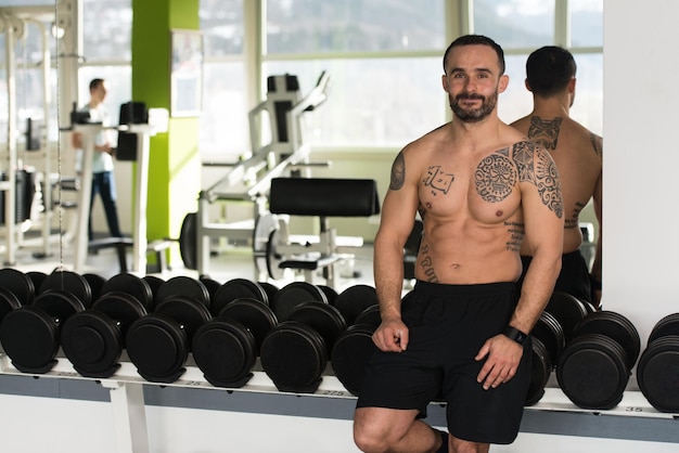 Beau jeune homme beau et séduisant avec un corps musclé relaxant dans la salle de sport