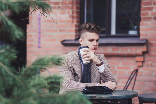 Beau jeune homme buvant du café à l'extérieur