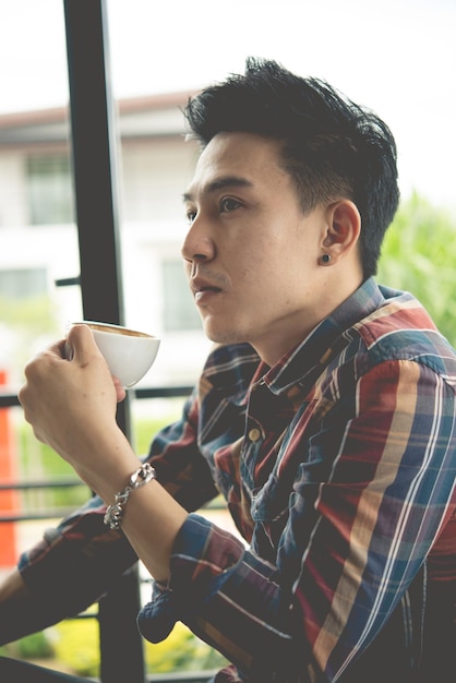 Beau jeune homme buvant du café sur le salon jeune moderne à la modetemps pour se détendre et repenser quelque chose de lifedrink pour un style vintage fraisremplissage d'épia sombre