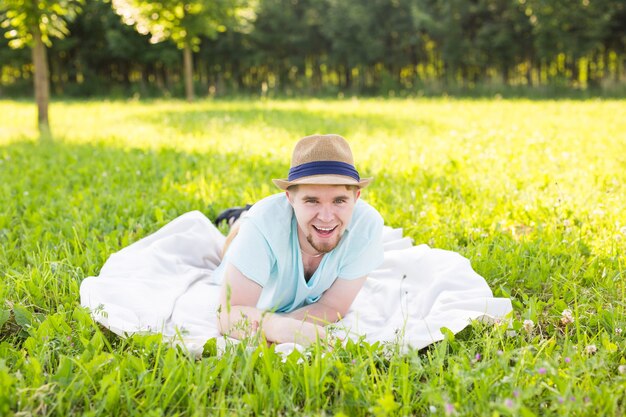 Beau jeune homme à la campagne, devant le champ portant une chemise, regardant la caméra en souriant