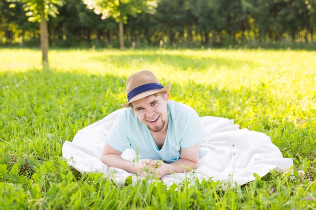 Beau jeune homme à la campagne, devant le champ portant une chemise, regardant la caméra en souriant