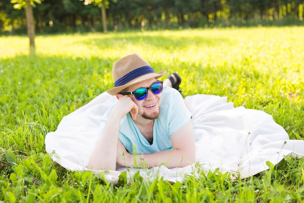 Beau jeune homme à la campagne, devant le champ portant une chemise, regardant la caméra en souriant