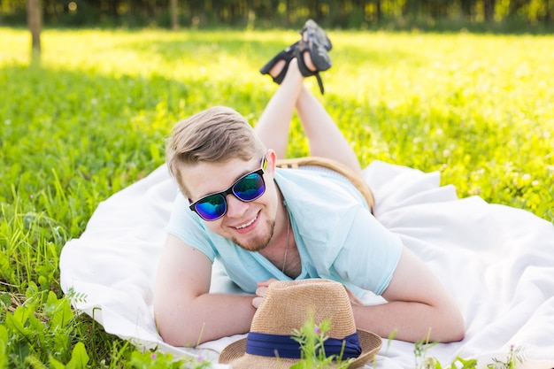 Beau jeune homme à la campagne, devant le champ portant une chemise, regardant la caméra en souriant