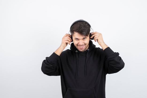 Beau jeune homme à capuche noir portant de gros écouteurs de musique sans fil