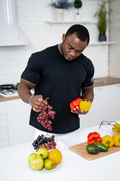 Beau jeune homme choisissant des fruits sains freah. Homme séduisant cuisinant des repas de fruits végétariens.