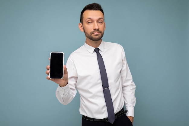 Beau jeune homme cool et heureux à la recherche de vêtements élégants décontractés debout isolé sur