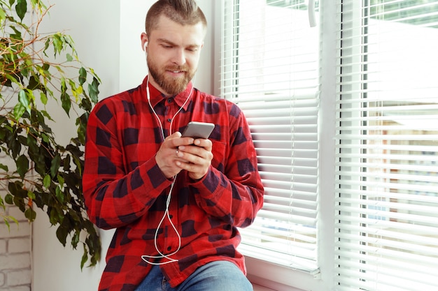 Beau, jeune homme, dans, écouteurs, tenue, téléphone portable