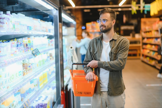 Un beau jeune homme dans une épicerie choisit des produits alimentaires