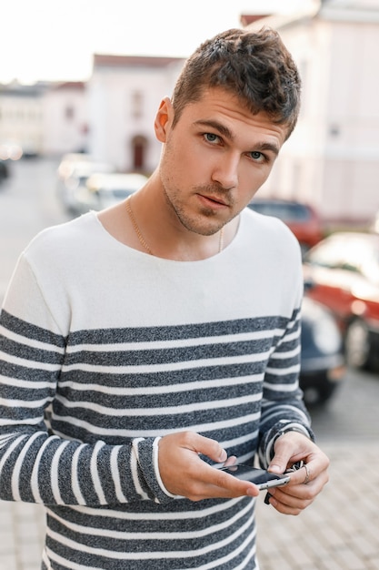 Beau jeune homme dans un pull garde votre téléphone.