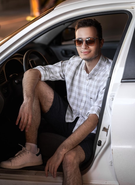 Beau jeune homme dans une voiture blanche