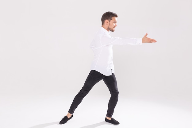 Beau jeune homme dansant sur une surface blanche