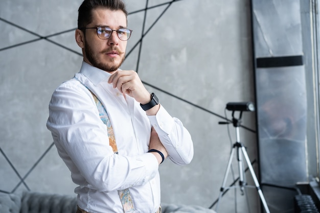 Beau jeune homme debout contre le gris