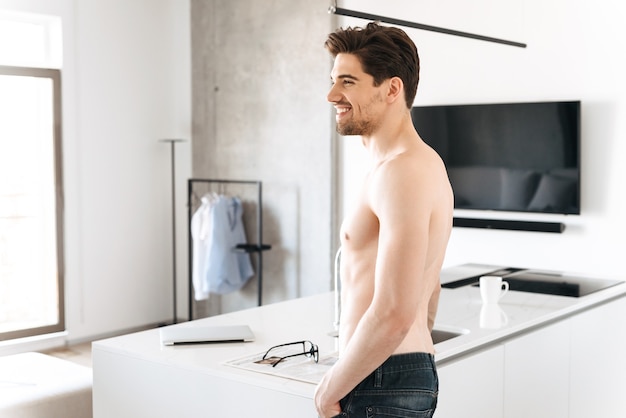 Beau jeune homme debout dans la cuisine