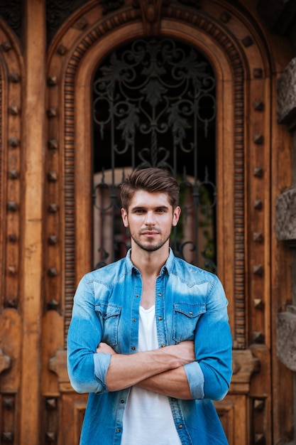 Beau jeune homme debout devant la belle porte en bois