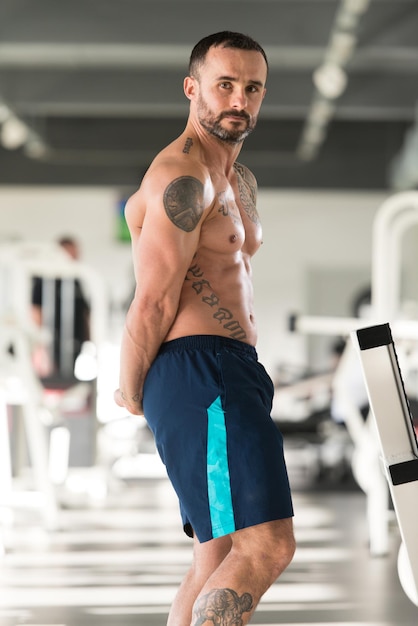 beau, jeune homme, debout, fort, dans, les, gymnase, et, flexion, muscles, musclé, athlétique, bodybuilder, forme physique, modèle, poser, après, exercices