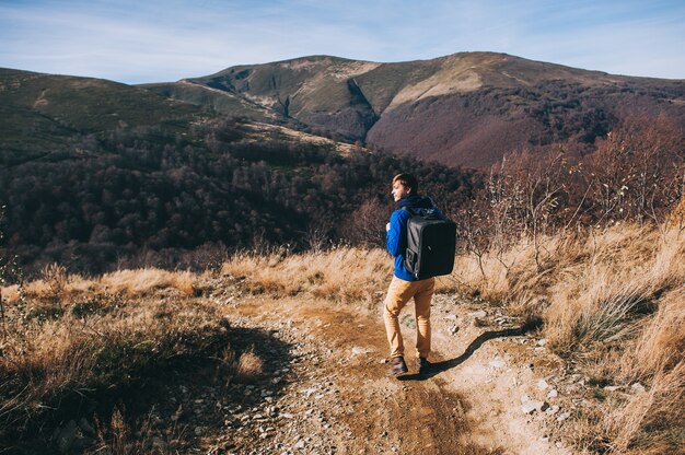 Beau jeune homme debout sur une roche, jouissant de la vue