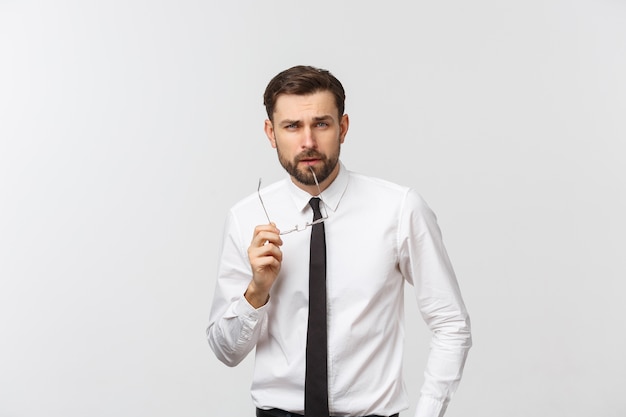 Un beau jeune homme du millénaire de race blanche dans des verres et un T-shirt blanc isolé sur un espace studio gris, regarde copie vierge