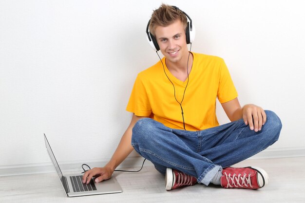 Beau jeune homme écoutant de la musique sur fond gris