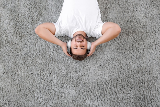 Beau jeune homme écoutant de la musique tout en se relaxant à la maison