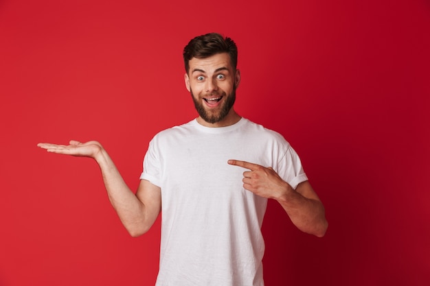 Beau jeune homme émotionnel pointant. Regardant la caméra.