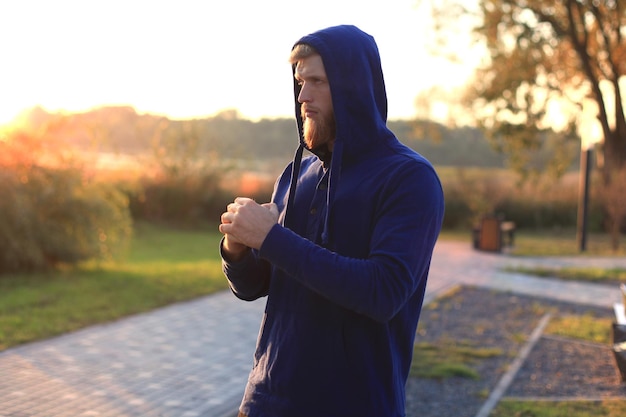 Beau jeune homme faisant des exercices d'étirement avant de courir en se tenant debout à l'extérieur