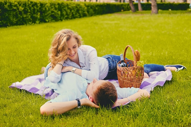 Beau jeune homme et femme blonde en pique-nique dans un parc d'été.