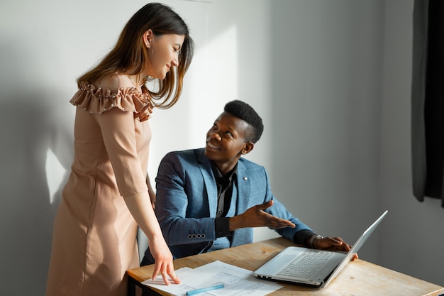 beau jeune homme et femme travaillant au bureau avec ordinateur portable