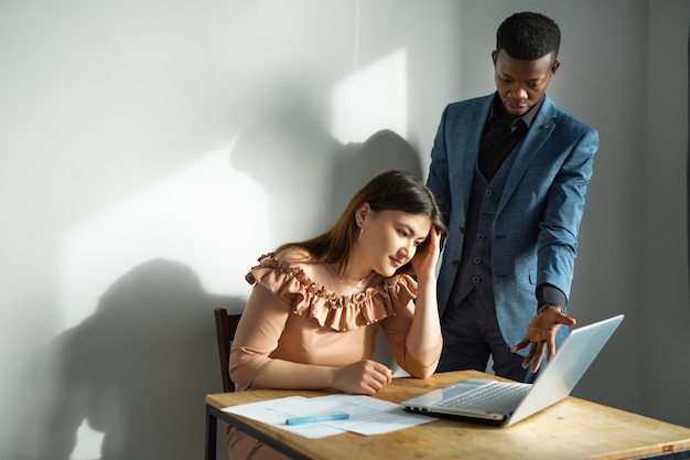 beau jeune homme et femme travaillant au bureau avec ordinateur portable