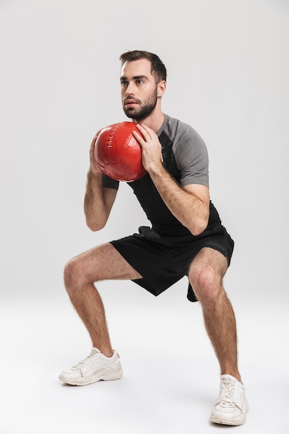 beau jeune homme de fitness sportif posant, faire des exercices avec ballon.