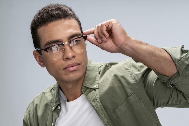 Beau jeune homme fixant ses lunettes d'une main