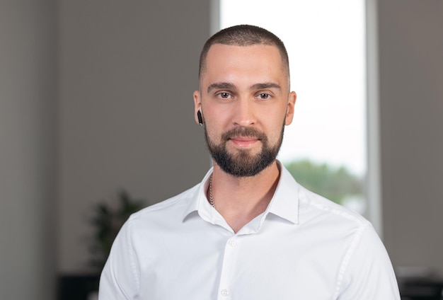 Beau jeune homme fort avec une barbe dans une chemise blanche avec un casque