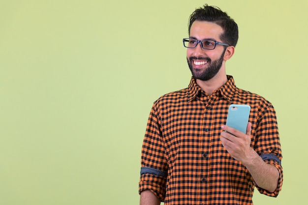 Beau jeune homme hipster persan barbu contre un mur de couleur