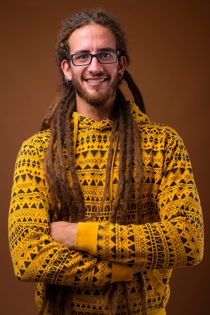 Beau jeune homme hispanique avec des dreadlocks sur fond marron