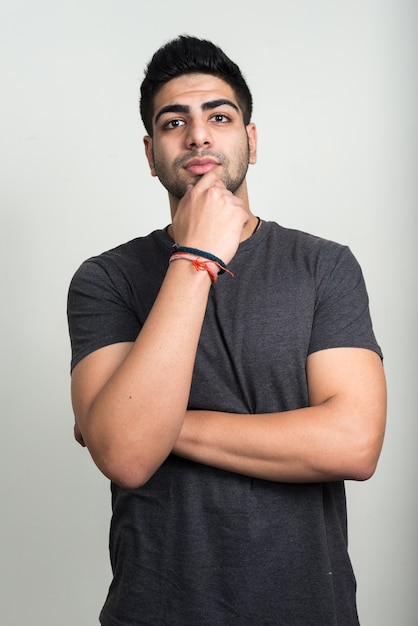 Beau jeune homme indien barbu contre un mur blanc