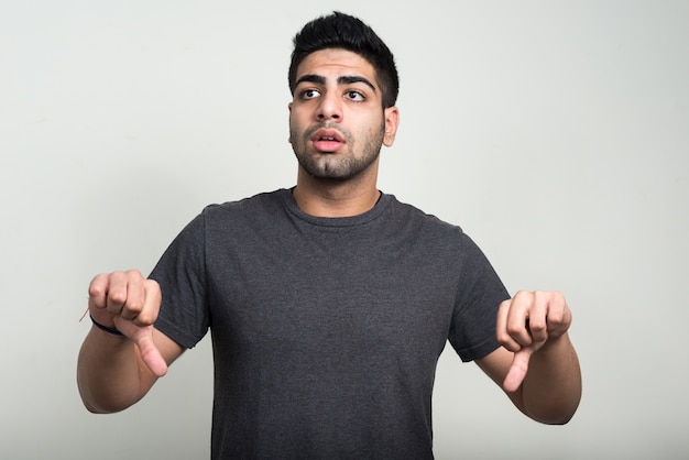 Beau jeune homme indien barbu contre un mur blanc