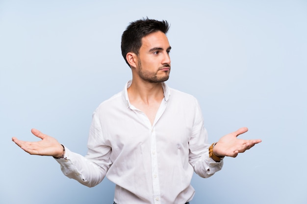 Beau jeune homme isolé bleu malheureux de ne pas comprendre quelque chose