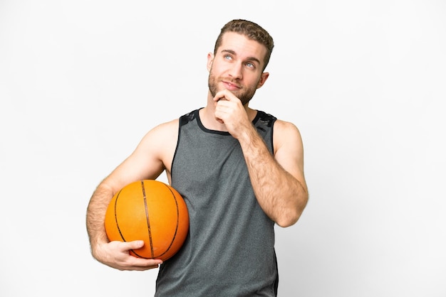 Beau jeune homme jouant au basket-ball sur fond blanc isolé et levant les yeux