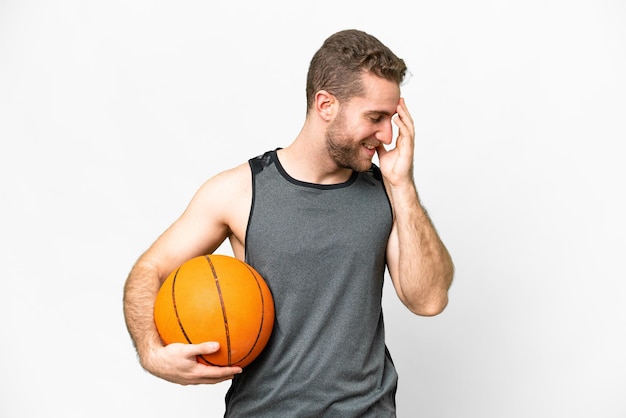 Beau jeune homme jouant au basket-ball sur fond blanc isolé en riant