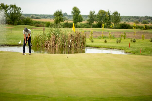 Beau jeune homme jouant au golf