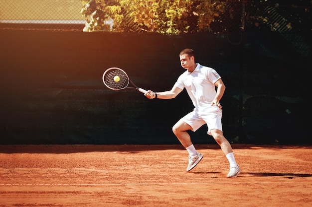 Beau jeune homme jouant au tennis.